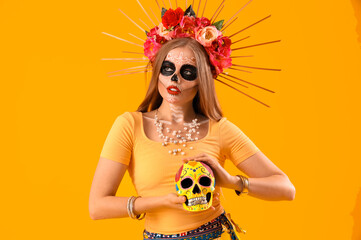 Canvas Print - Beautiful young woman with painted skull on yellow background. Celebration of Mexico's Day of the Dead (El Dia de Muertos)