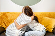 © ADDICTIVE STOCK - Two women sitting on a sofa while hugging each other