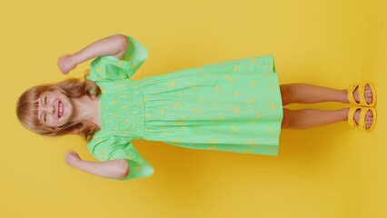 Wall Mural - Young preteen child girl kid shouting, raising fists in gesture I did it, celebrating success, winning, birthday, lottery jackpot goal achievemen. Children isolated on yellow background. Vertical shot