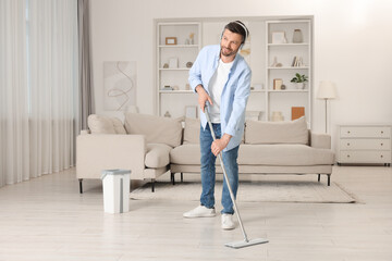 Poster - Enjoying cleaning. Man in headphones listening to music and mopping floor at home