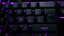 Man's Hand Pressing The ENTER Key On A Purple Backlit Black Computer Keyboard. Selective Focus.