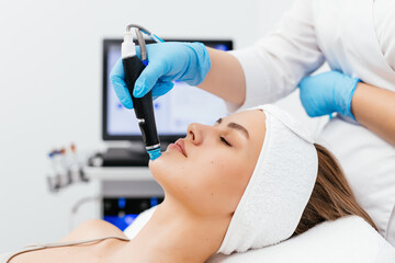 Close-up shot of a young beautiful woman lying on a couch in a cosmetology center. Young woman doing hydrofacial therapy in beauty spa.