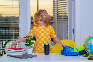 Fototapete - School child 7-8 years old puts school supplies in a backpack go back to school. Little student doing homework at home.