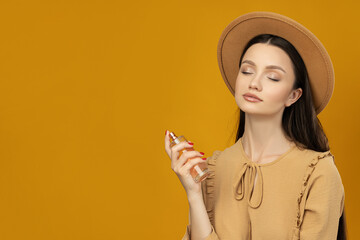 Wall Mural - Attractive girl in a hat with perfume in her hand