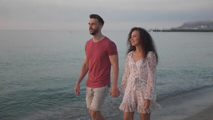 Poster - Beautiful couple walking on sea beach at sunset, slow motion effect. Camera moving left