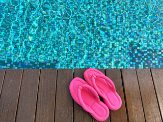 Canvas Print - Clear rippled water in swimming pool and pink flip-flops on wooden deck outdoors, above view. Space for text