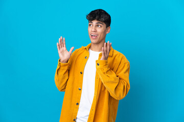 Young man over isolated blue background with surprise facial expression