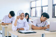 © Queenmoonlite Studio - Group of multiethnic Asian high school students having test or exam in classroom
