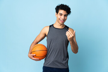 Young Venezuelan man isolated on blue background playing basketball and doing coming gesture