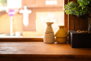 Wall Mural - Ceramic stonewares and bonsai tree are placed on the wooden table closed to the house window with day light outside. There are for Japanese style home decoration. Interior furniture object photo.