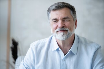 Wall Mural - Portrait of happy mature man sitting on sofa at home.