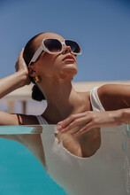 Beautiful Woman With Dark Hair In Elegant Swimming Suit And Accessories Relaxing In Swimming Pool In Summer Beach Club