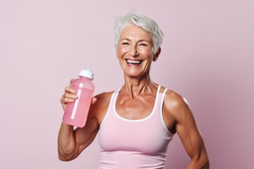 Happy matured white hair woman holding bottle and smiling. Healthy fitness and diet concept . Fit senior woman drinking water after workout.