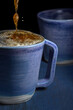 Close up of blue porcelain coffee cups with froth on a black background