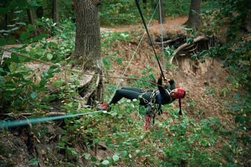 Wall Mural - Climbing in the forest. Woman is in the forest using the safety equipment