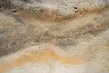Close Up Of Rock With Cream, Orange And Brown Wavey Pattern And Crack Through Middle
