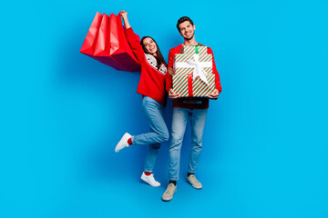 Poster - Full size photo of two overjoyed satisfied couple raising up shopping bags guy hold presents on xmas isolated on blue color background