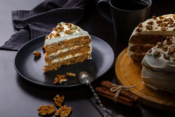 Wall Mural - Carrot cake with butter cream and walnuts on a dark background