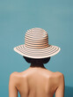 © Anna Hoychuk - Woman Wearing Striped Dress and Straw Hat on blue Water Background. Generative ai