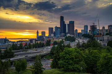 Wall Mural - Dramatic sunset over the Seattle downtown skyline, with traffic on the I-5 and I-90 freeway interchange, viewed from Dr. Jose Rizal Bridge.