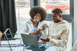 © LIGHTFIELD STUDIOS - two jolly friends in casual outfits with coffee cup in hands looking at laptop, business concept
