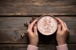 Top view of female hands holding a cup of hot cocoa on rustic wooden table with copy space. Generative Ai