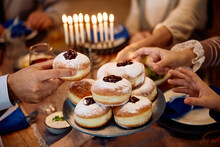 Close Up Of Jewish Family Having Traditional Sufganiyah For Dessert On Hanukkah.