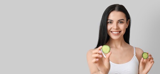 Poster - Beautiful young woman with cucumber slices on grey background with space for text. Cosmetology concept