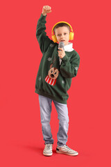 Poster - Cute little boy in headphones with microphone singing on red background