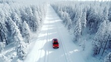 Aerial View Of Red Car Driving Through The White Snow Winter Forest On Country Road 