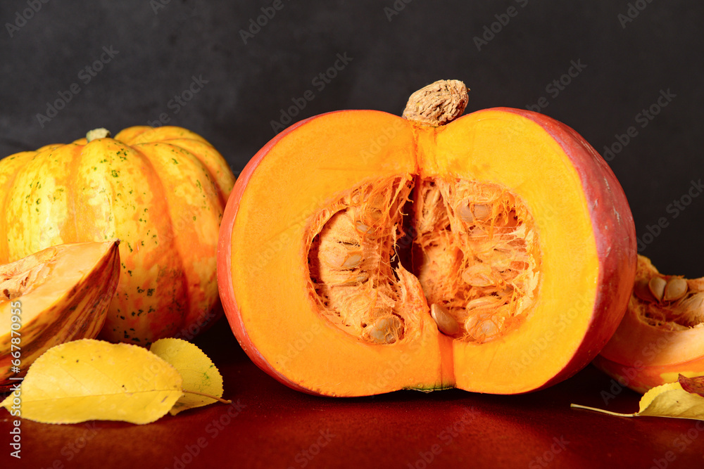 Fresh pumpkins and autumn leaves on red table