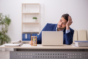 Wall Mural - Young male employee in time management concept