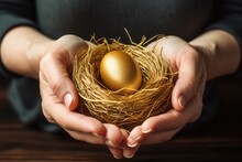 Womans Hands Holding Golden Egg In A Nest