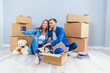 © gorynvd - Young couple taking selfies in their new home while sitting among cardboard boxes. Happy attractive young couple is moving, making a selfie, cuddling and smiling.