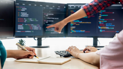 female programer taking a note while young skilled web developer present program while computer disp