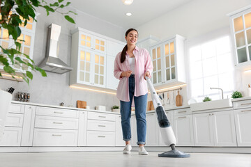 Canvas Print - Happy woman cleaning floor with steam mop in kitchen at home, low angle view