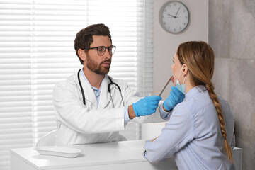 Canvas Print - Doctor examining woman`s oral cavity with tongue depressor in hospital