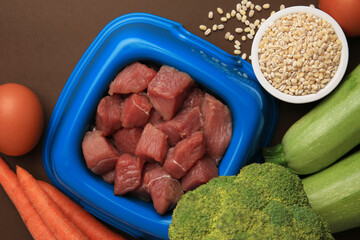 Poster - Raw meat in bowl and healthy products for pet on brown background, flat lay