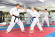 © JackF - Caucasian man and senior woman in kimono sparring during group karate training. Woman and teenage boy fighting in background.