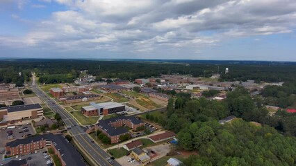 Wall Mural - ascending aerial footage of Grambling State University with red brick buildings surrounded by green trees and grass, cars driving on the street, blue sky and powerful clouds in Grambling Louisiana USA