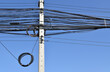 messy electrical cables wiring on concrete electric pole with clear blue sky background, roadside chaos power lines in bangkok, thailand