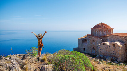 Wall Mural - Traveler caucasian woman in Greece- typical orthodox church and mediterranean sea