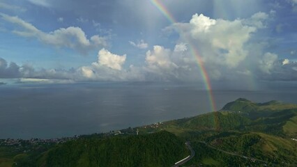Wall Mural - Beautiful Rainbow 4k Right to Left Panning Aerial of Rainbow in the Rain over Ocean and Mountains.