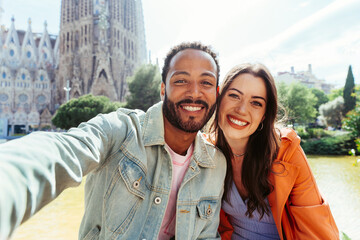 Multiracial beautiful happy couple of lovers dating at Sagrada Familia, Barcelona - Multiethnic tourists travelling in Europe and visiting a city in Spain, concepts about tourism and people lifestyle