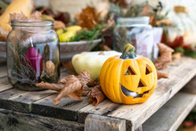 Hallowen Jack O Lantern And Other Autumn Decorations Including Pumpkins, Jars With Candles, Leaves, Apples On A Wooden Table