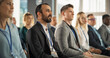 © Gorodenkoff - Multiethnic Male Technology Conference Attendee Sittign In Crowd And Listening to Presentation Of Innovative Gadget. Middle Eastern Man Looking For Investment Opportunities At International Tech Forum