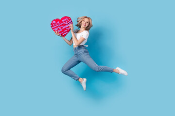 Poster - Full length photo of pretty shiny lady wear white blouse jumping high holding heart pinata isolated blue color background