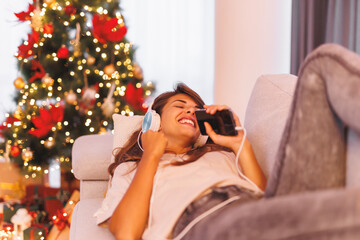 Wall Mural - Woman listening to the music and singing by the Christmas tree