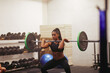 © Flamingo Images - Muscular young woman strength training with weights at a gym