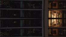 Ascending Fly Along High Rise Apartment Building At Night. People In Flats With Lighted Windows. Abstract Computer Effect Digital Composed Footage